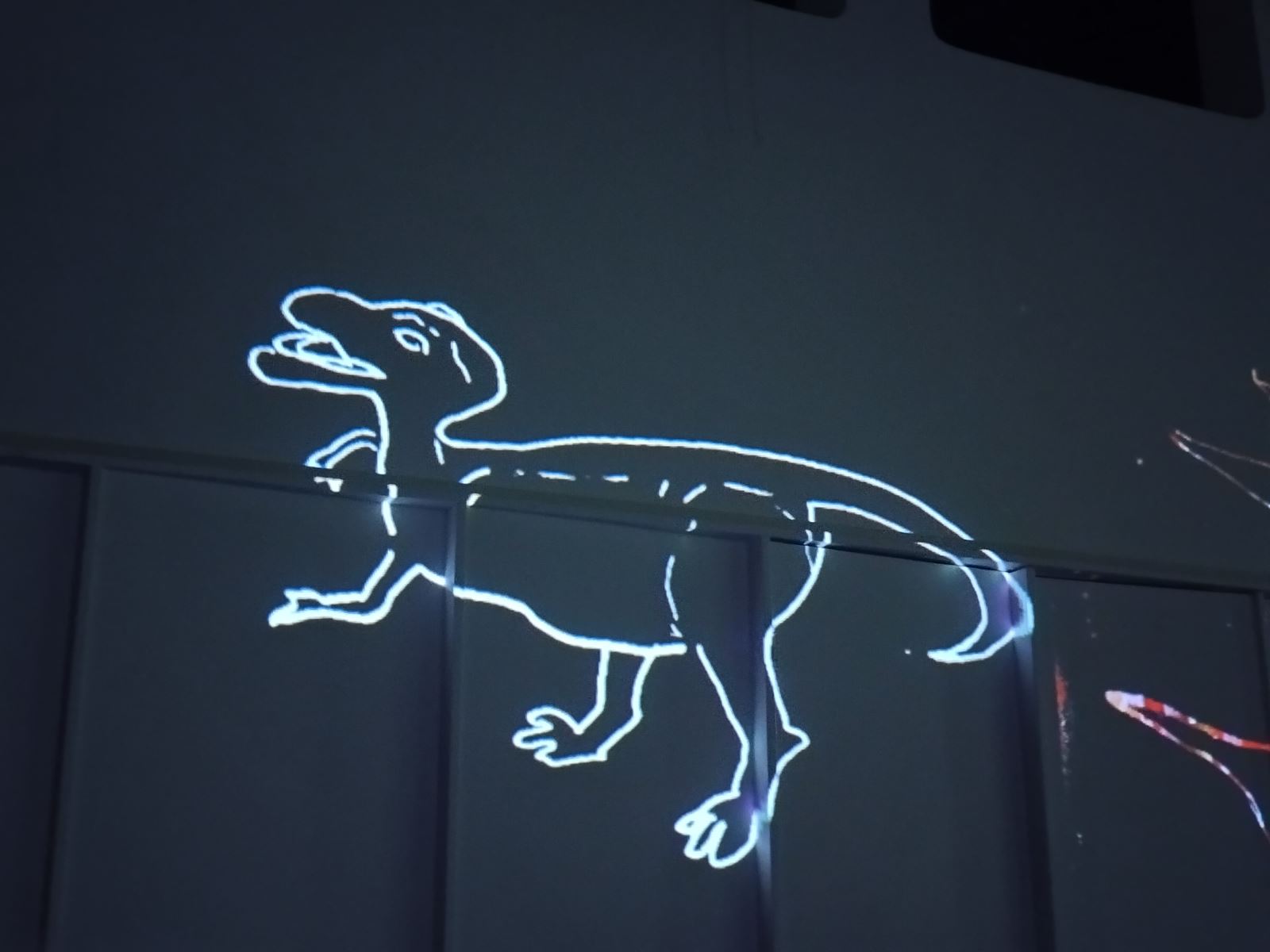a white dinosaur outline projected onto a wall